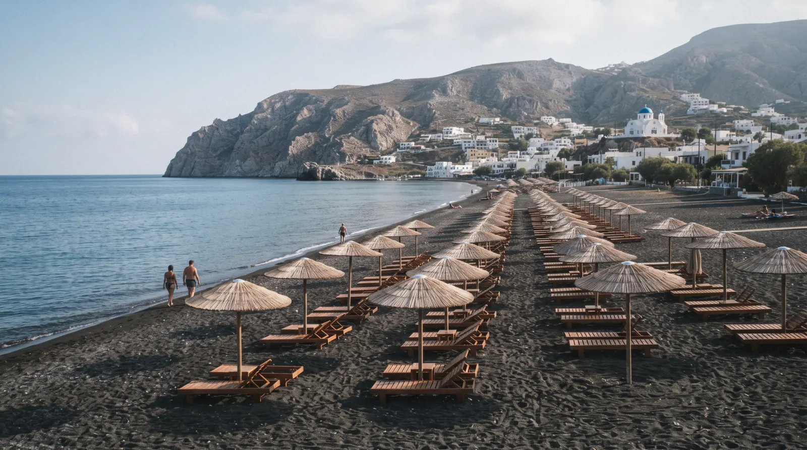 Perissa black sand beach at 09:00 with rows of empty straw umbrellas, perissa beach, Santorini Greece