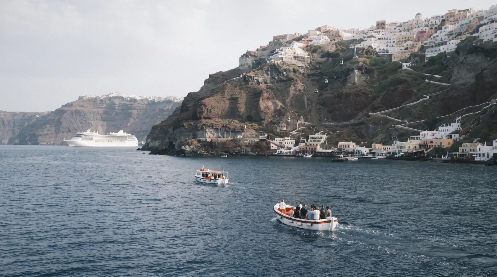 Two tender boats crossing from an anchored cruise ship to the Old Port below Fira at 09:00, santorini cruise port, Santorini Greece