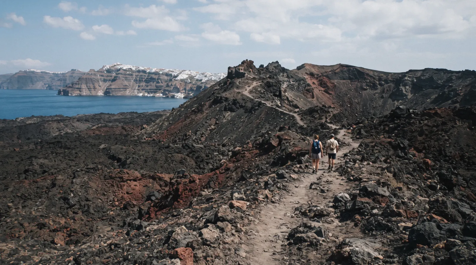 The black and rust lava fields and crater rim of Nea Kameni at 10:30, santorini volcano, Santorini Greece