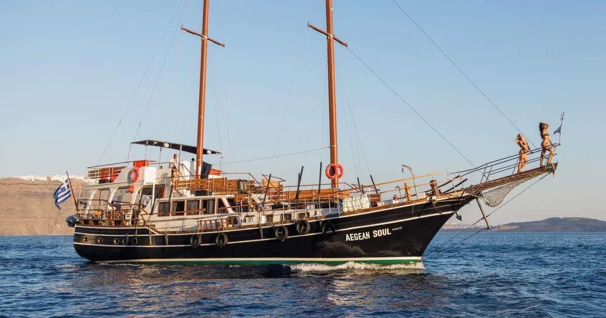 Excursion boat moored at Nea Kameni on a volcanic islands cruise with hot springs, Santorini Greece